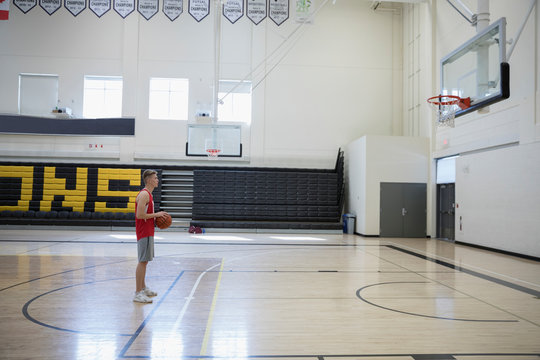 Male College Basketball Player Practicing Free Throws In Gymnasium