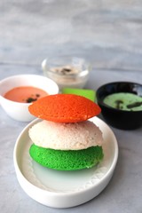 Tiranga Idli or Tricolor Idly cooked in  Indian National Flag colors - saffron or orange, white and green. Served with tiranga chutney. Concept for Indian Independence or Republic day greeting card. 