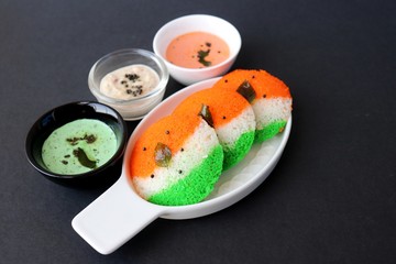 Tiranga Idli or Tricolor Idly cooked in  Indian National Flag colors - saffron or orange, white and green. Served with tiranga chutney. Concept for Indian Independence or Republic day greeting card. 