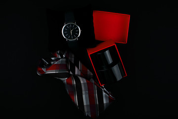 Set of men's accessories,necktie, perfumes and watch on a black background.bottle of black perfume on a dark background in a red box.