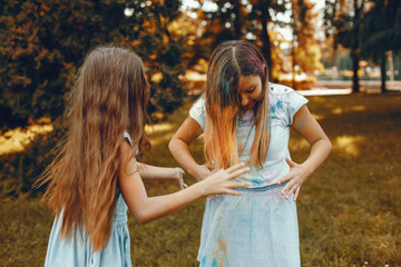 Beautiful girls with a colorful dry paints. Friends have fun in a summer park