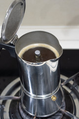 Mokapot coffee brewing on a stove isolated on brown background.
