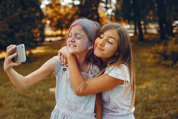 Beautiful girls with a colorful dry paints. Friends have fun in a summer park