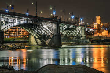Nocne zdjęcie oświetlonego mostu Poniatowskiego w Warszawie - obrazy, fototapety, plakaty