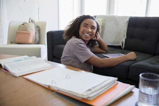 Portrait smiling teenage girl using digital tablet on living room sofa