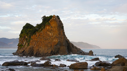 volcanic mountainous islands in the blue water of the Pacific Ocean. tropical islands of Japan overgrown with green plants against a beautiful sunset sky. Aburatsu