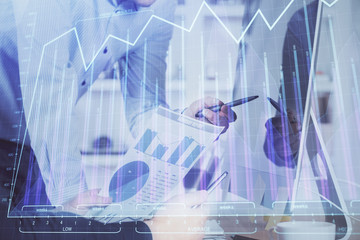 Double exposure of chart with businessman typing on computer in office on background. Concept of hard work.