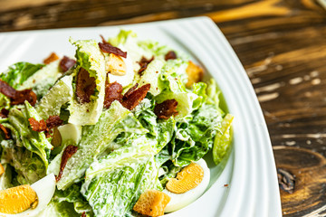 Healthy Caesar salad made of fresh vegetables on wood table