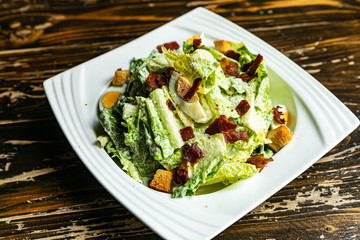 Healthy Caesar salad made of fresh vegetables on wood table