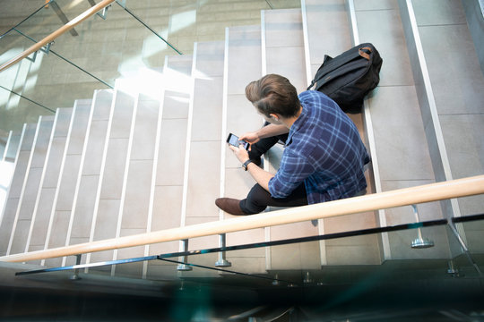 Male College Student Texting On Stairs