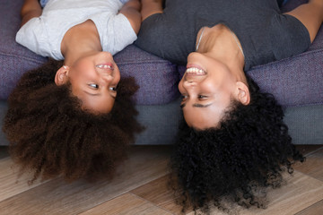 Happy African American mom and kid lying upside down