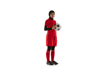 Arabian female soccer or football player isolated on white studio background. Young woman holding the ball, training, practicing in motion and action. Concept of sport, hobby, healthy lifestyle.