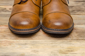 Rounded nose of men's brown shoes on a wooden background close-up with a copy of the space