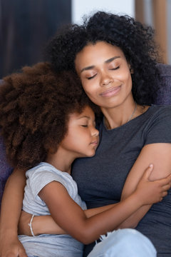 Black Mom And Small Daughter Hugging Tenderly On Couch