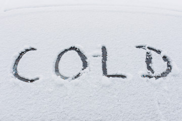 Snow covered car with word COLD on window
