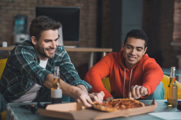 Joyful delighted men eating pizza at home