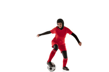 Obraz na płótnie Canvas Arabian female soccer or football player isolated on white studio background. Young woman kicking the ball, training, practicing in motion and action. Concept of sport, hobby, healthy lifestyle.