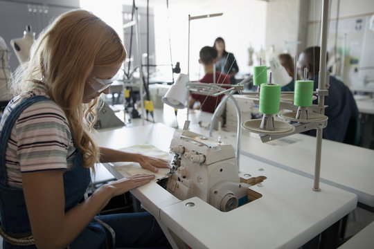Female fashion design student using serger in studio
