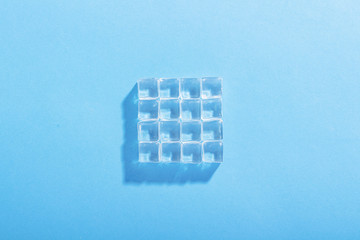 Ice cubes on a blue background. The concept of heat, cooling. Natural light. The shape of the square. Flat lay, top view