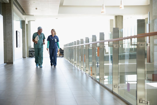 Surgeon and nurse walking and talking in hospital corridor