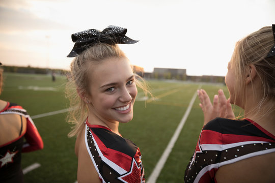 Portrait Smiling, Confident Teenage Girl High School Cheerleader On Sideline Of Football Field