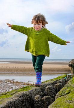 cute little girl doing balance exercises on the beach