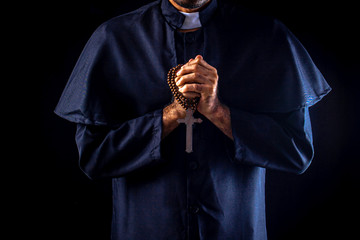 The priest holds the cross on black background For Halloween concepts