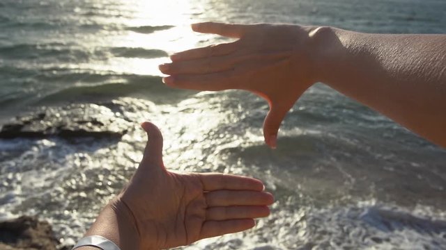 Closeup point of view video of woman forming square frame with her both hands isolated on sunny early morning sea water background. Full hd footage.