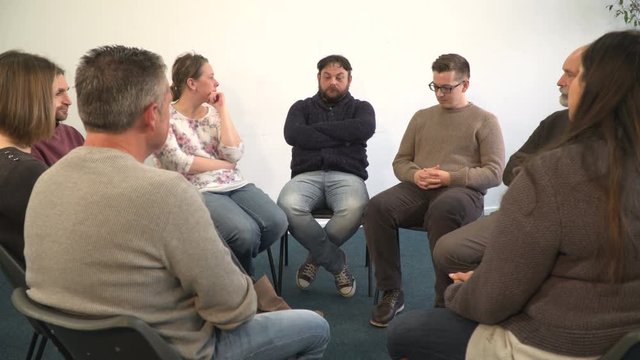 4K: Support group therapy - People sat in circle for recovery meeting - One man talks while the others listen. 