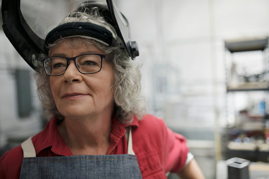 Close up confident senior female welder in welding mask looking away