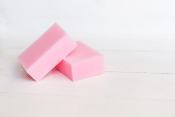 Two pink melamine sponges on a white wooden table. Useful household cleaning tools