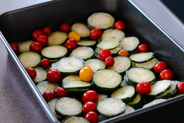 slices of zucchini and cherry tomatoes in oven tray ready to get cookied