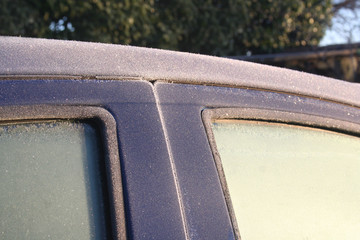 Blue car covered by frost on winter season. Side view of the car in selective focus.