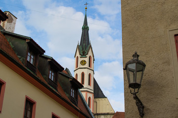 Tower of St. Vitus Church between some houses in a street in Cesky Krumlov, Czech Republic