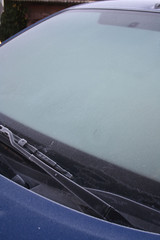 Blue car covered by frost on winter season. Side view of the car in selective focus.