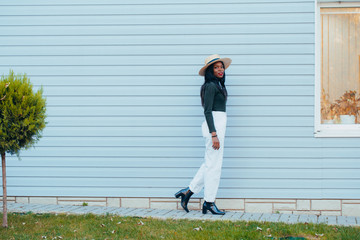 Beautiful young black african girl in white jeans and a hat with a happy smile on the street of the...