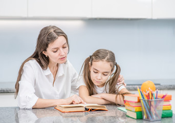 Mother helps her daughter doing homework at home
