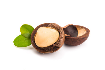 Macadamia nut with pieces and green leaves isolated on a white background