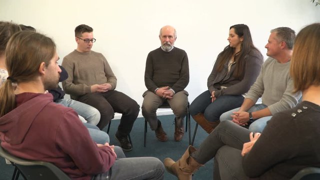 Support group people sat in circle for therapy Counselling session - One mature man talks while the others listen. Mental Heath, Social Issues