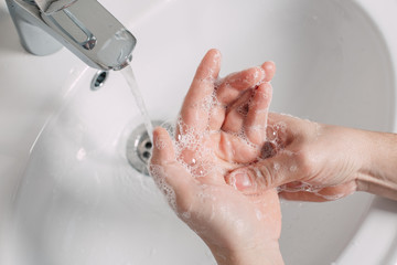 Hygiene concept. Washing hands with soap under the tap with water. handsome male hands and water in...