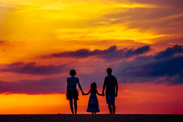 Happy family on meadow at summer sunset