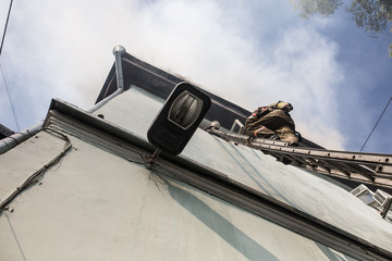 Firefighters on ladders in oxygen masks extinguish the fire in an old house in the middle of the city