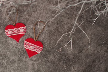 Holiday background for Valentine's Day on a gray cement background with white painted branches and a sheet of paper for text