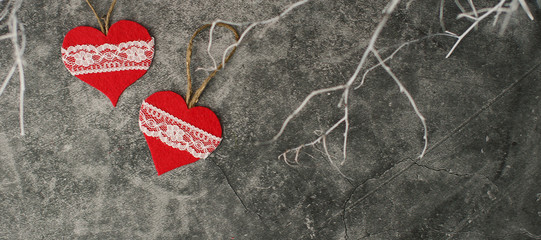 Holiday background for Valentine's Day on a gray cement background with white painted branches and a sheet of paper for text