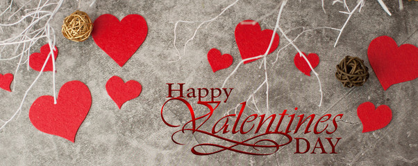 Holiday background for Valentine's Day on a gray cement background with white painted branches and a sheet of paper for text