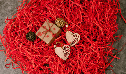 Holiday background for Valentine's Day on a gray cement background with red chopped wrapping paper and hearts.