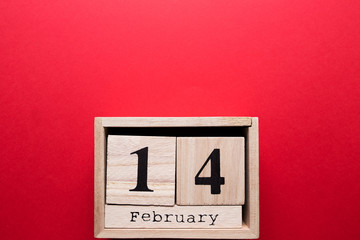 Wooden calendar with the inscription February 14 on a red isolated background.