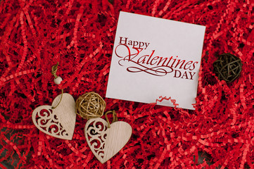 Holiday background for Valentine's Day on a gray cement background with red chopped wrapping paper and hearts.