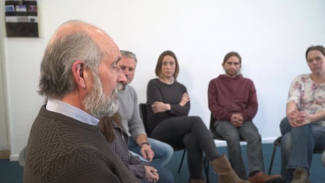 Support group people sat in circle for therapy Counselling session - One mature man talks while the others listen. Mental Heath, Social Issues