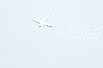 Minimal creative composition of one model toy airplane with color petals on a blue background